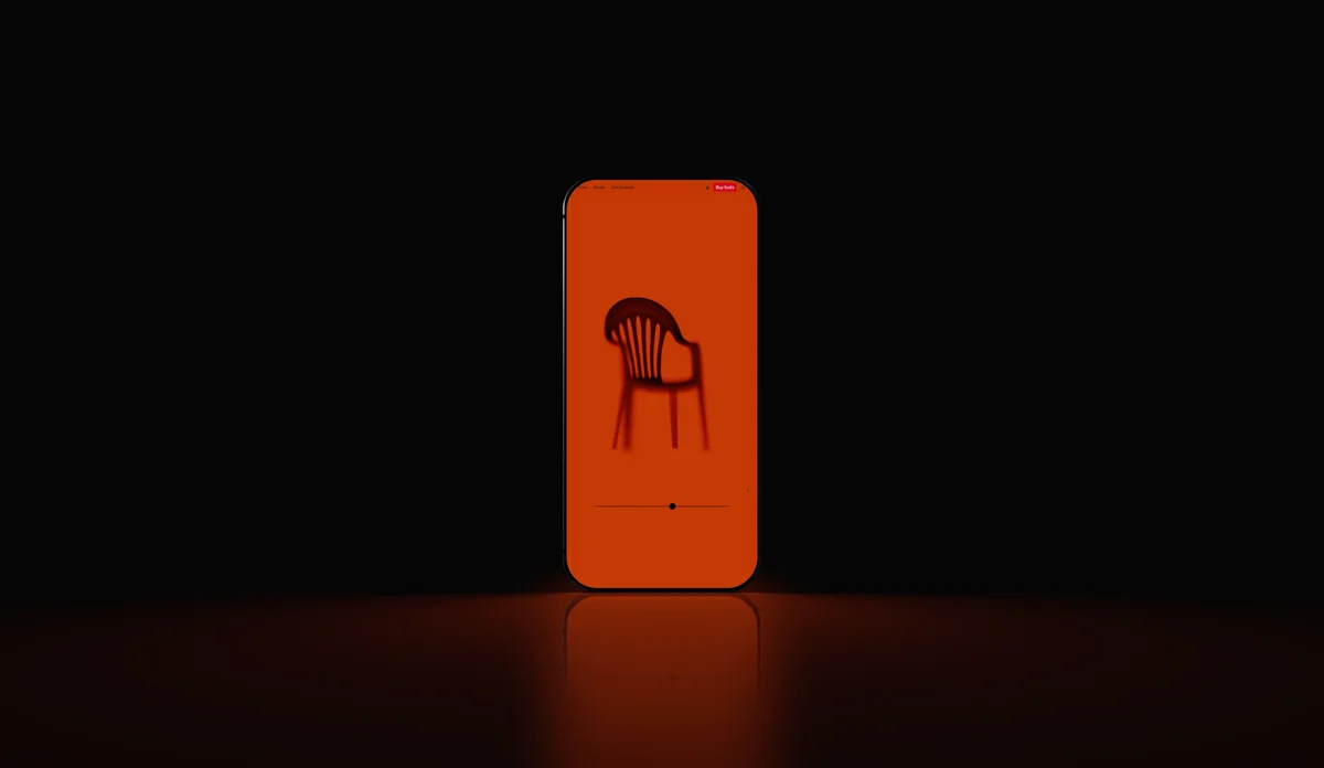 An orange phone standing in darkness, its glow pooling on a black floor.
