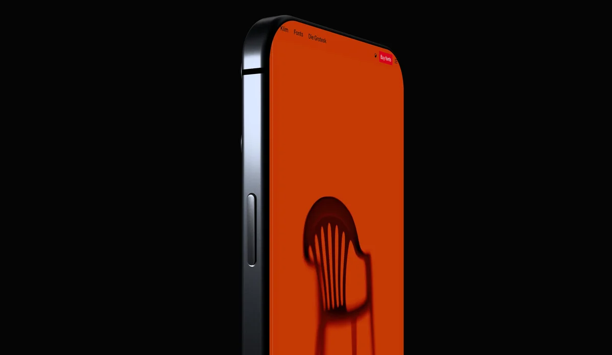 A close view of a phone's steel edge and side button beside its orange screen, in darkness.