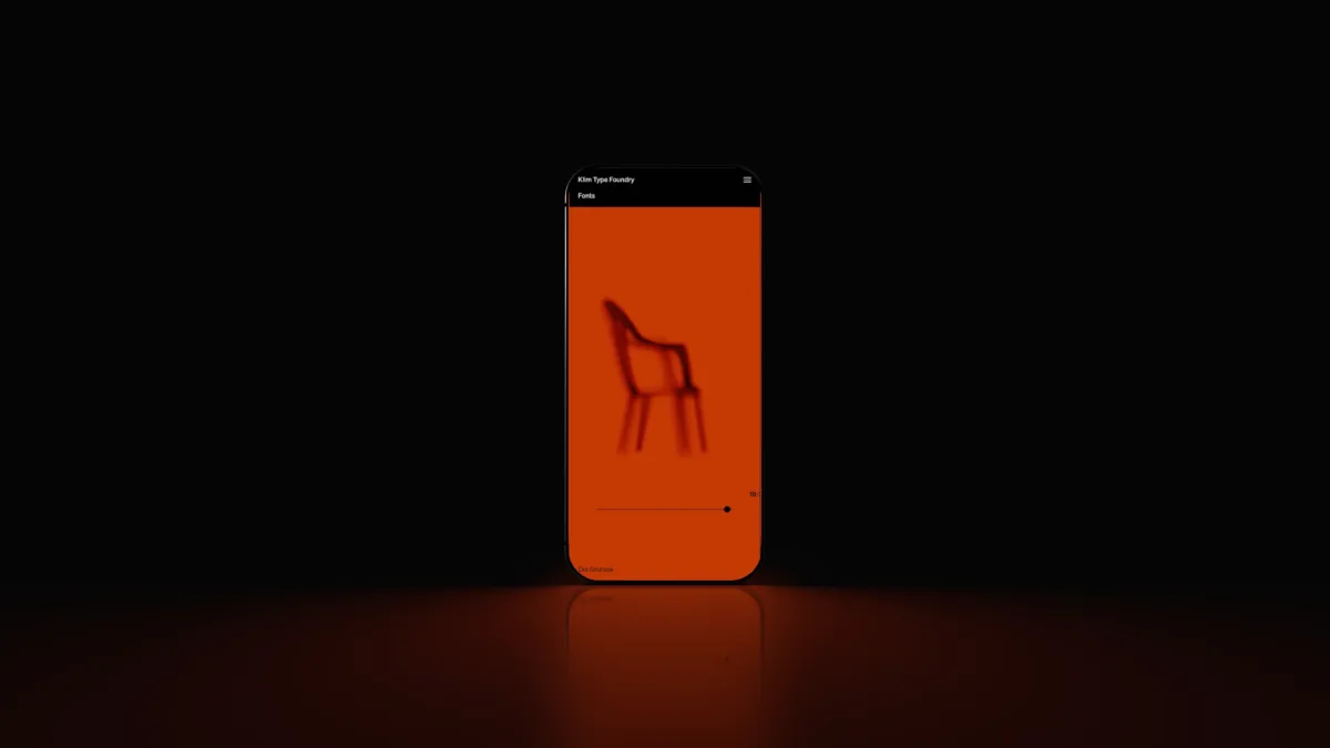 An orange phone standing in darkness, a chair on its screen, its red glow on the floor.